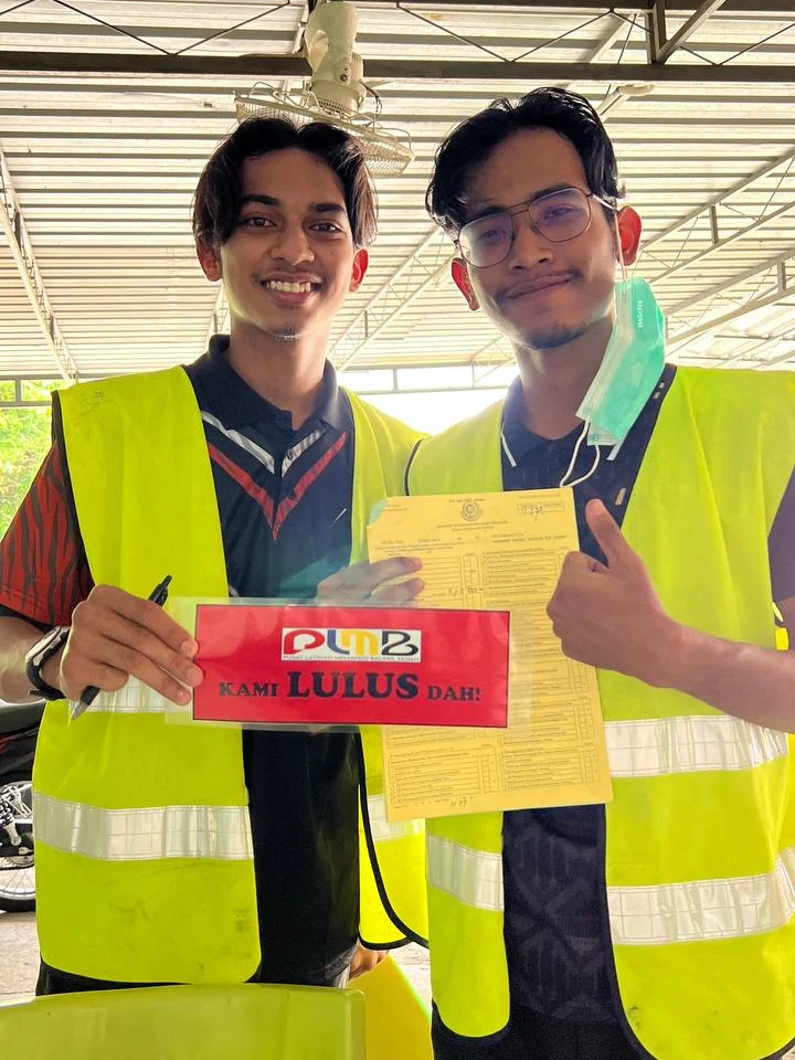 Pelajar PLMB yang baru lulus ujian JPJ, memegang papan 'Kami Lulus Dah!' dan borang ujian